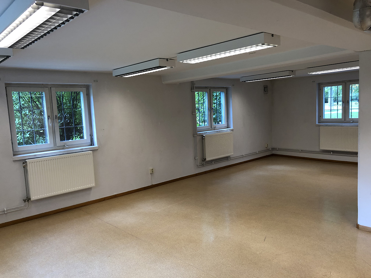 Del i lokal med vitmålade väggar och fönster med galler.